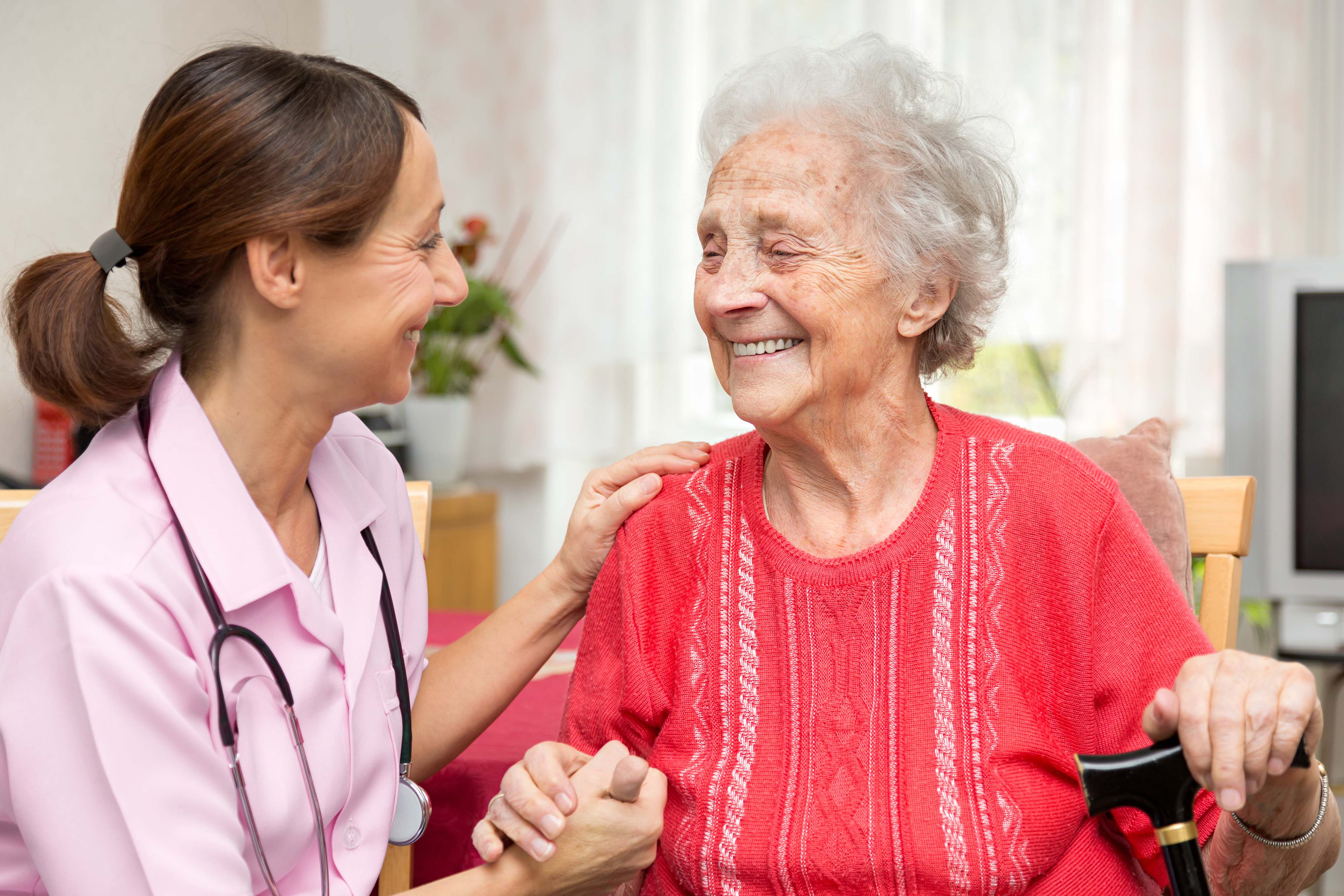 Eine Krankenschwester hilft einer älteren Frau mit ihrem Rollator.